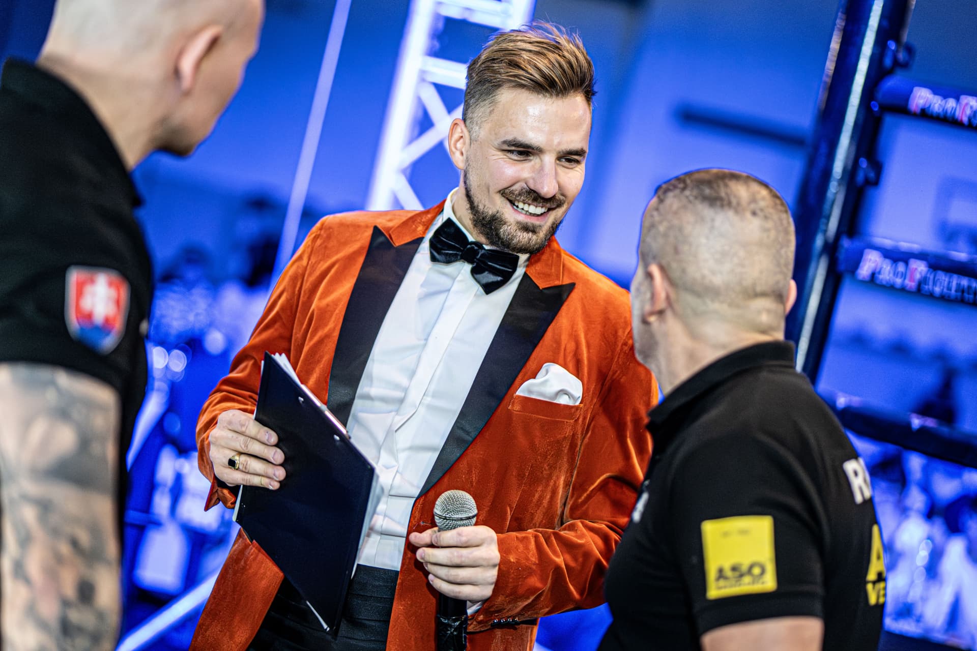 Ján Mrázik v oranžovom saku s mikrofónom a poznámkami tesne pred začatím akcie