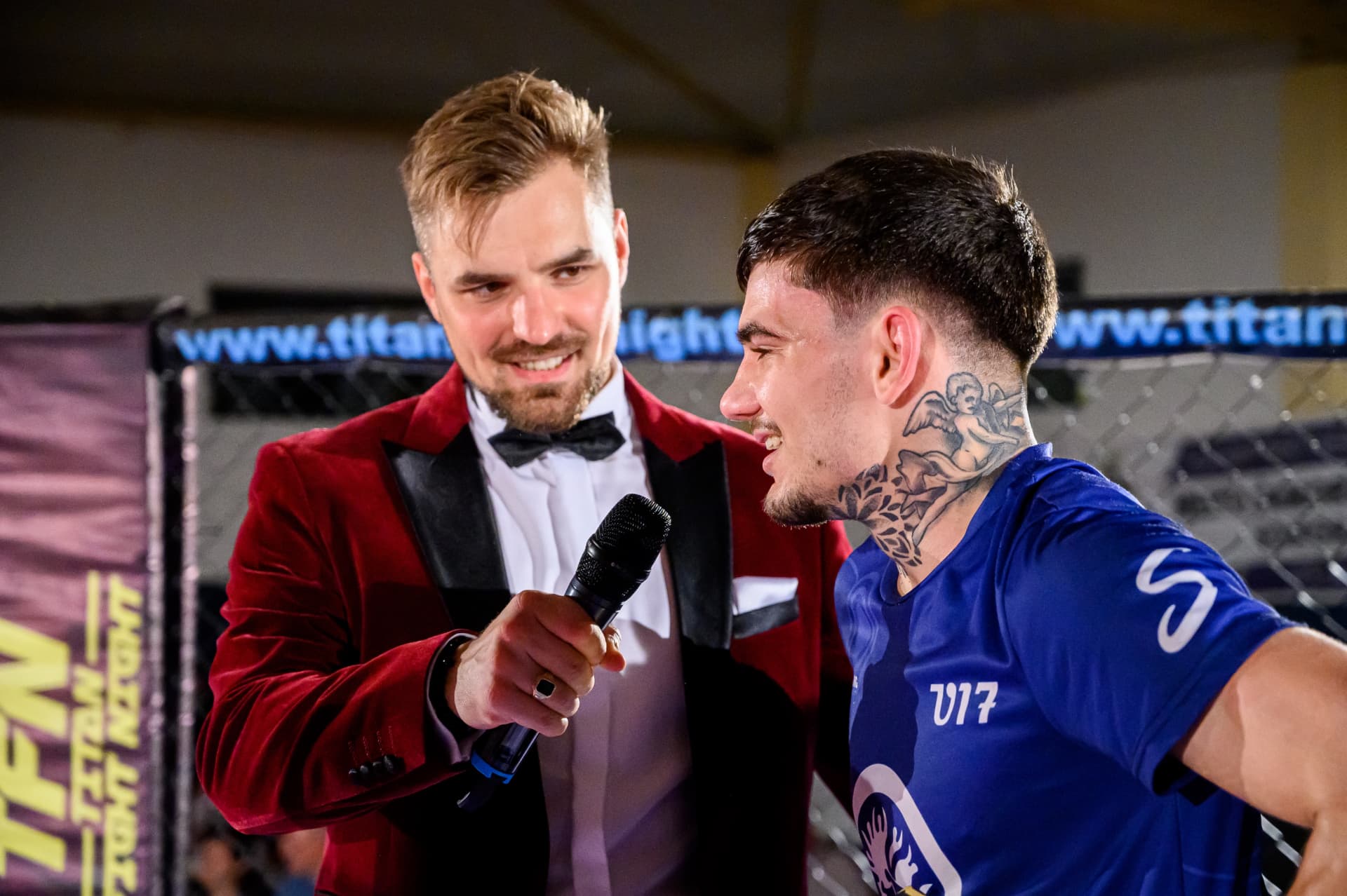Ján Mrázik moderuje turnaj bojových športov, v červenom saku drží mikrofón pri športovcovi